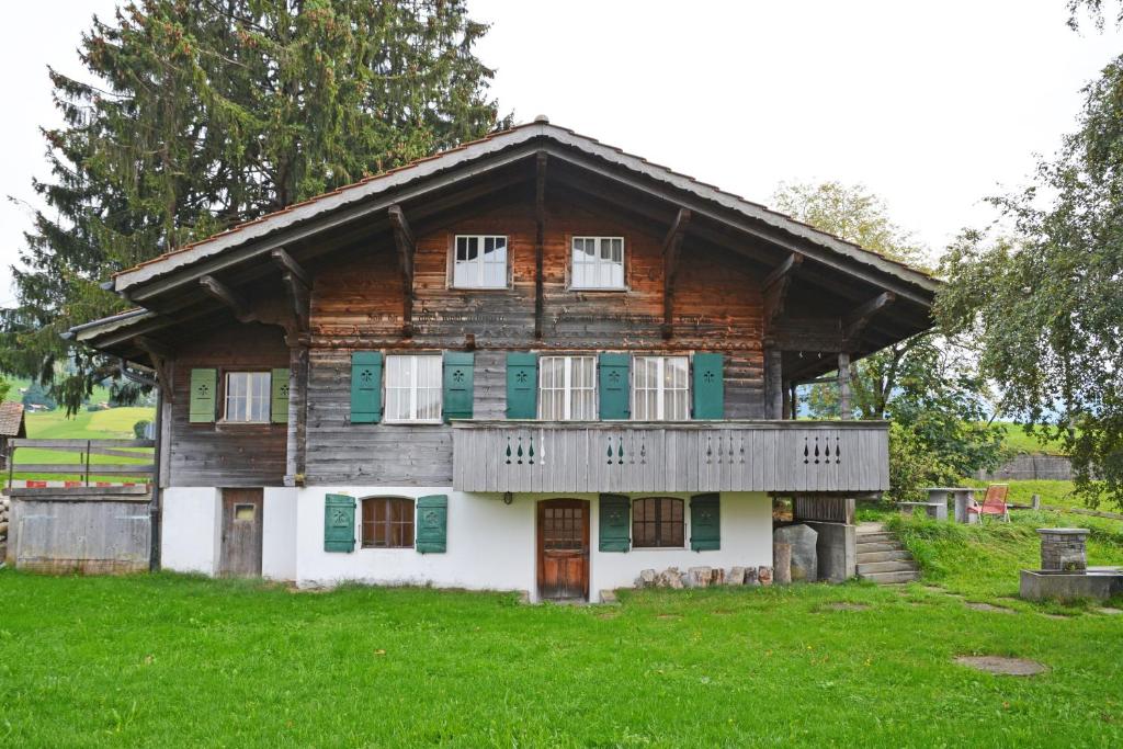 AeschiにあるTraditionelles Chalet Schärmtanneの緑の長戸とポーチのある古い丸太家