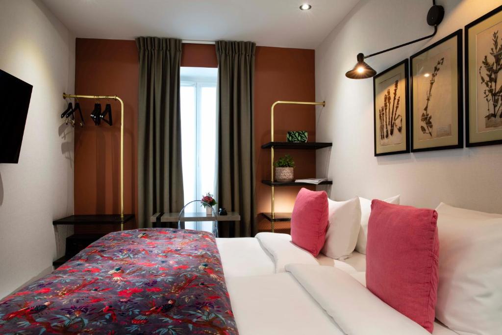 a living room with a white couch with pink pillows at Hôtel Maxim Quartier Latin in Paris