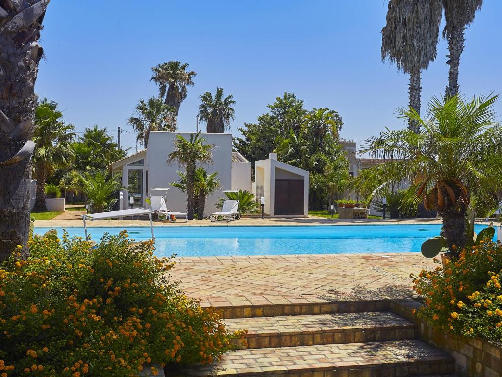 a swimming pool with palm trees and a house at Lush Villa with Private Swimming Pool in Marsala Sicily in Marsala