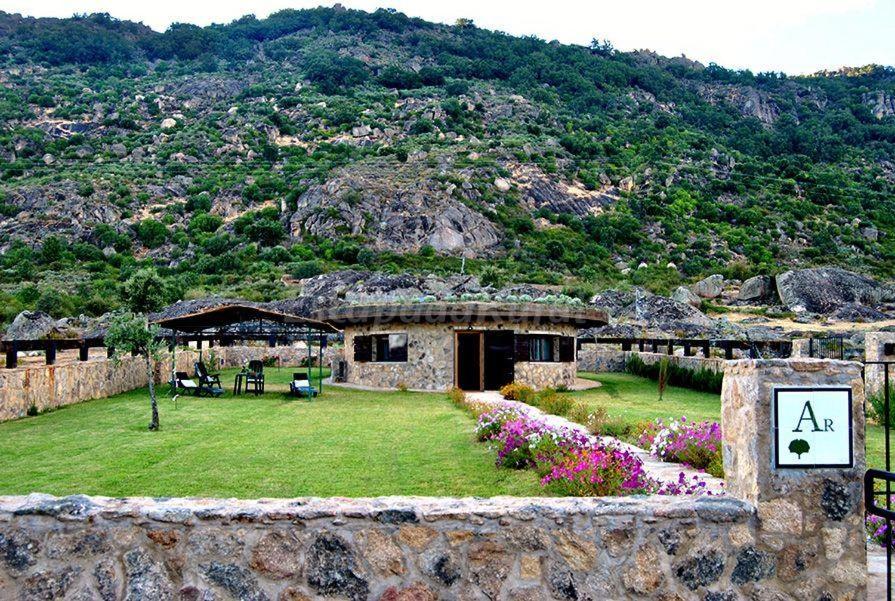 ein Steinhaus mit einem Garten und einem Berg in der Unterkunft Casa rural LA DEHESA in Cilleros