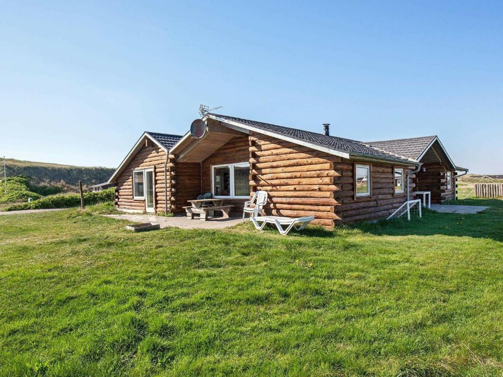 a log cabin in a field with a grass yard at 10 person holiday home in Harbo re in Harboør