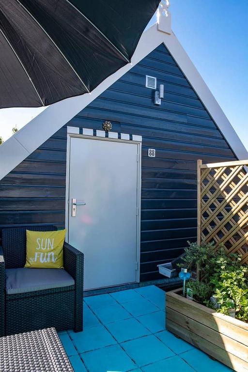 a blue building with a white door on a patio at VakantieStudio 88 in Kamperland