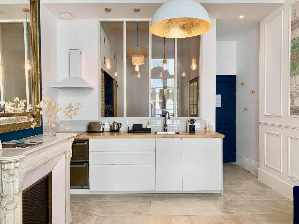 a kitchen with white cabinets and a fireplace at Home Chic Home - Les Suites de La Comédie in Montpellier