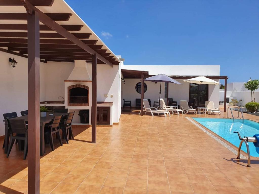 un patio con mesa y sillas y una piscina en Villa Santana en Playa Blanca