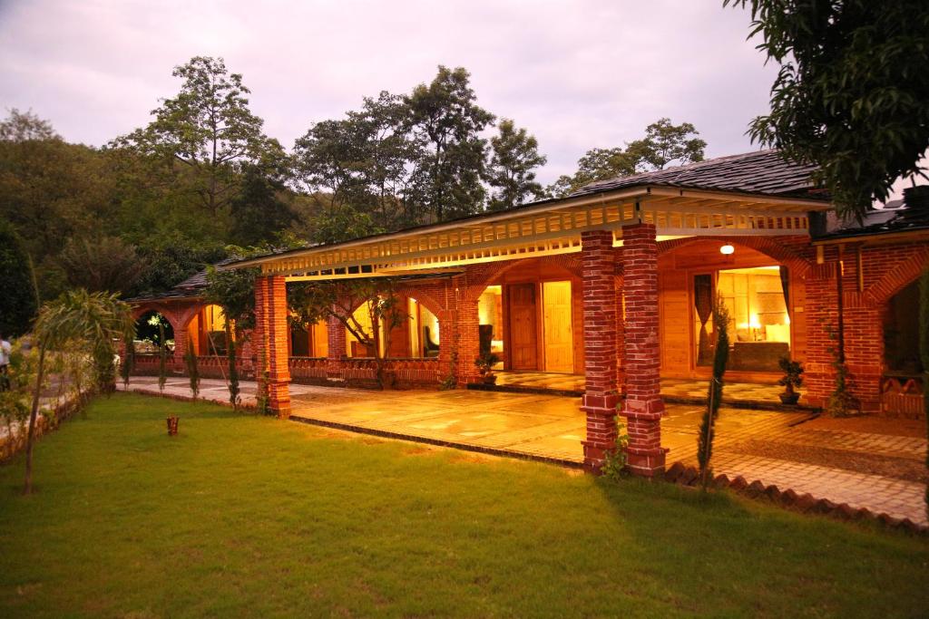 a brick house with a porch and a lawn at The Sylvan Retreat in Dehradun