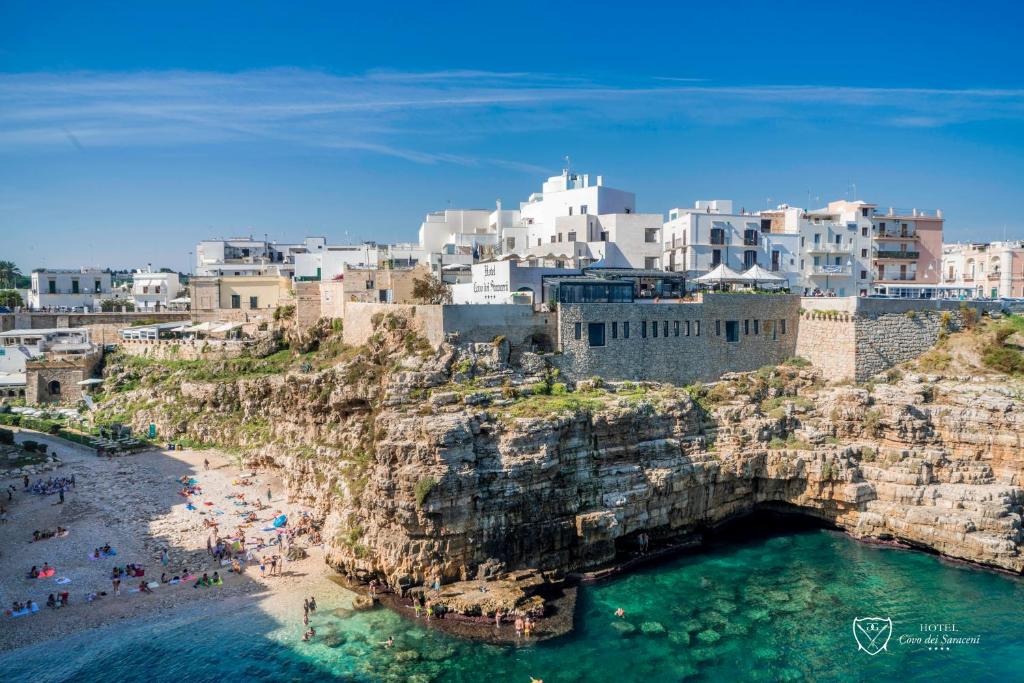 un gruppo di persone su una spiaggia vicino all'acqua di Covo dei Saraceni a Polignano a Mare