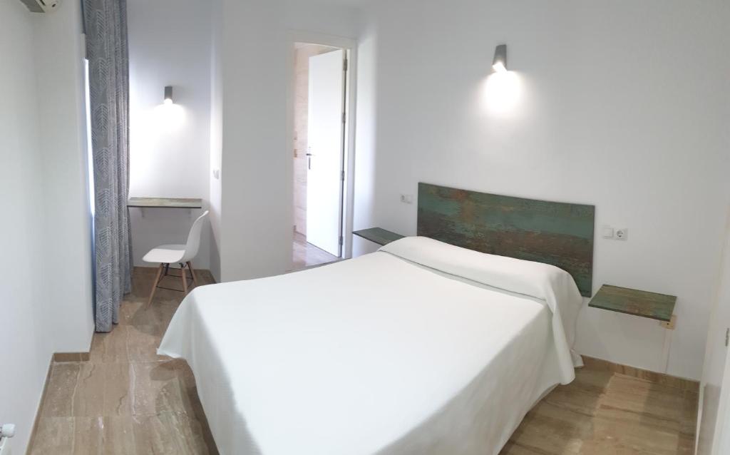 a white bedroom with a white bed and a chair at Hotel La Lancha in Córdoba