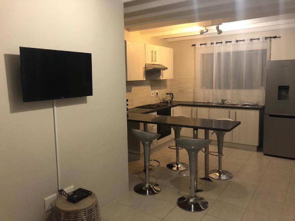 a kitchen with a table and a television on a wall at The Square 11 Private Suite in Port Elizabeth
