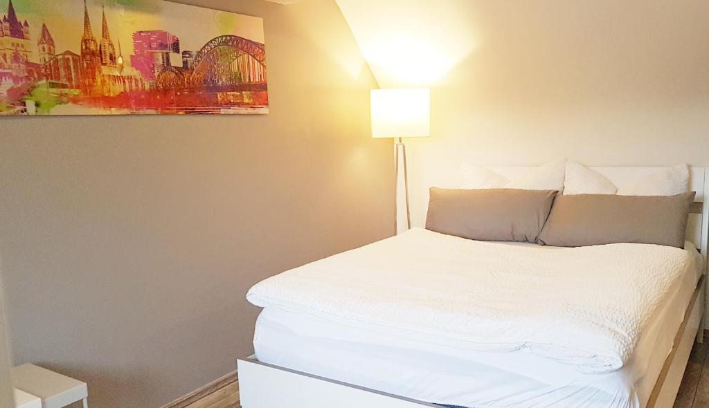 ein Schlafzimmer mit einem weißen Bett und einer Lampe in der Unterkunft Zwei schicke Apartments mit Parkplatz in Köln