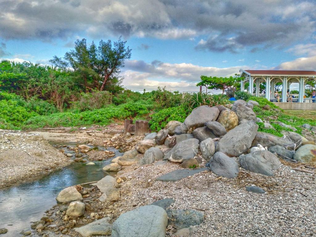 a river with rocks and a building in the background at Yue Ya Wan Homestay in Checheng