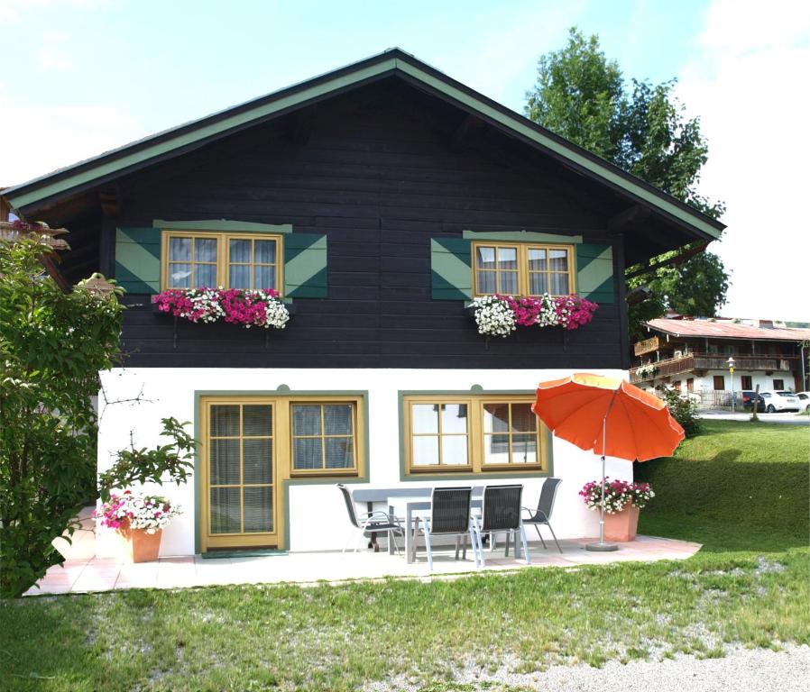 a black and white house with chairs and an umbrella at Alpen Chalet ELLMAU Zentrum in Ellmau