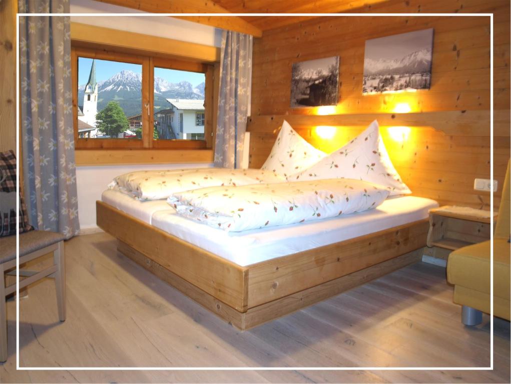 a wooden bed in a room with a window at Alpen Chalet ELLMAU Zentrum in Ellmau