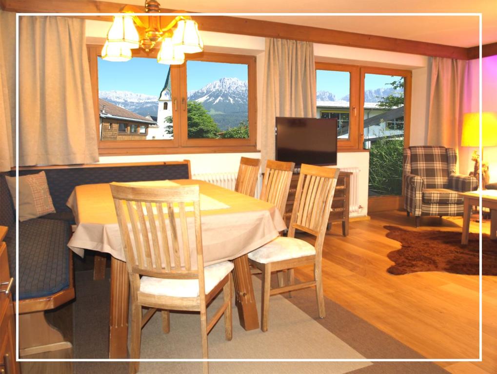 a dining room with a table and chairs and a television at Alpen Chalet ELLMAU Zentrum in Ellmau