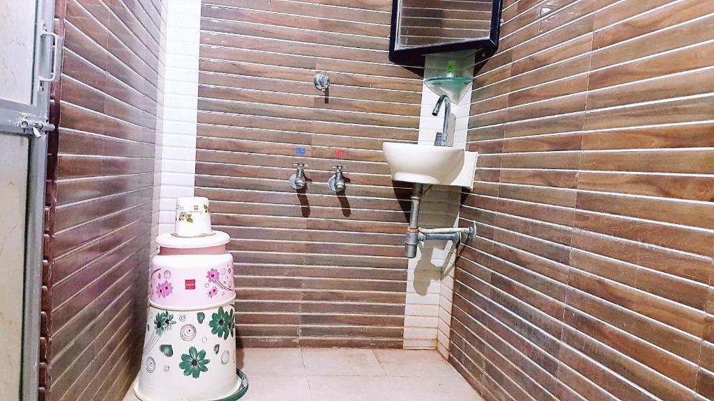 a bathroom with a sink on a wooden wall at Dream Vision Guest House in Diu