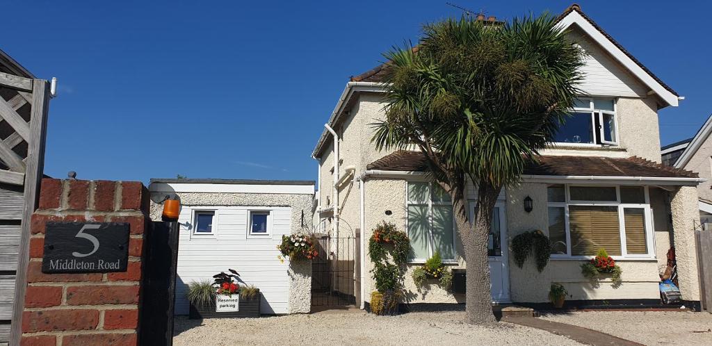 a house with a palm tree in front of it at Felpham Guest House - Self Catering in Bognor Regis