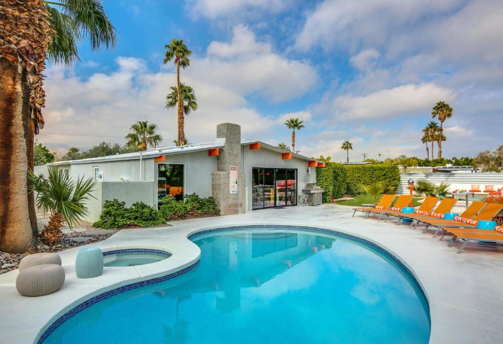 una piscina di fronte a una casa con palme di Iconic Mid-century Modern Vacation Home with Pool! a Palm Springs