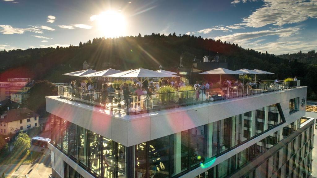 Leute stehen auf einem Gebäude mit der Sonne am Himmel in der Unterkunft Hotel am Remspark in Schwäbisch Gmünd