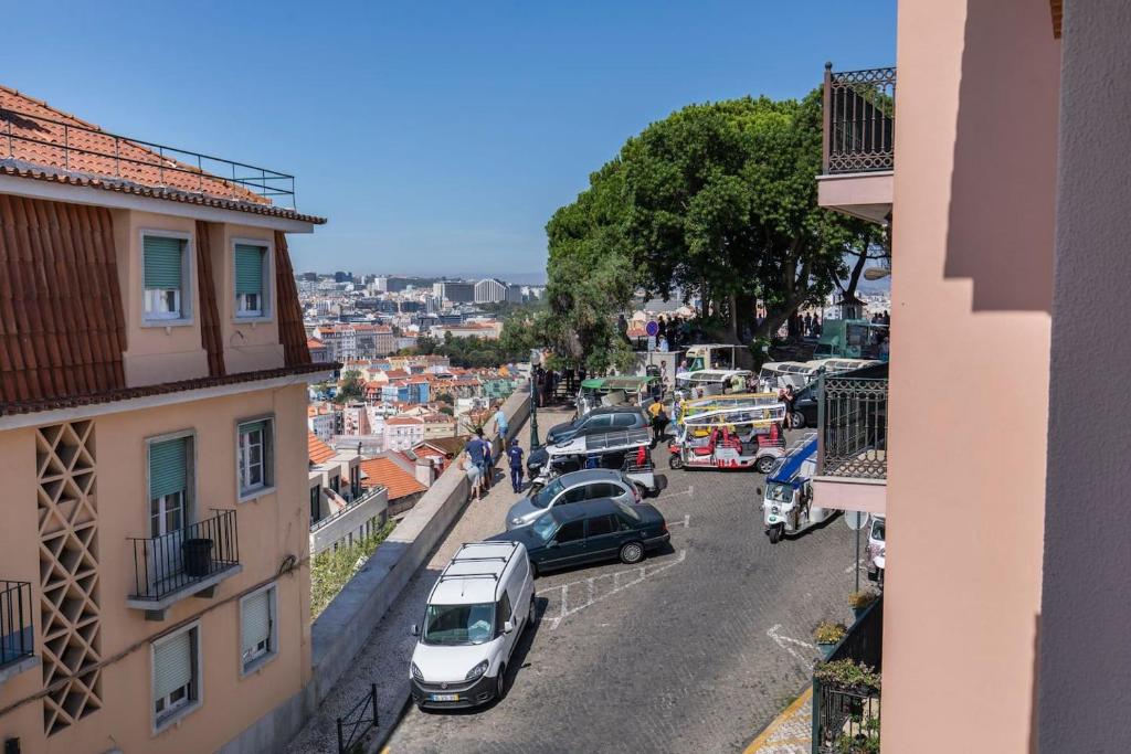 une rue de la ville avec des voitures garées sur le côté de la route dans l'établissement LovelyStay - Sunshine Residence in the Heart of Graça, à Lisbonne