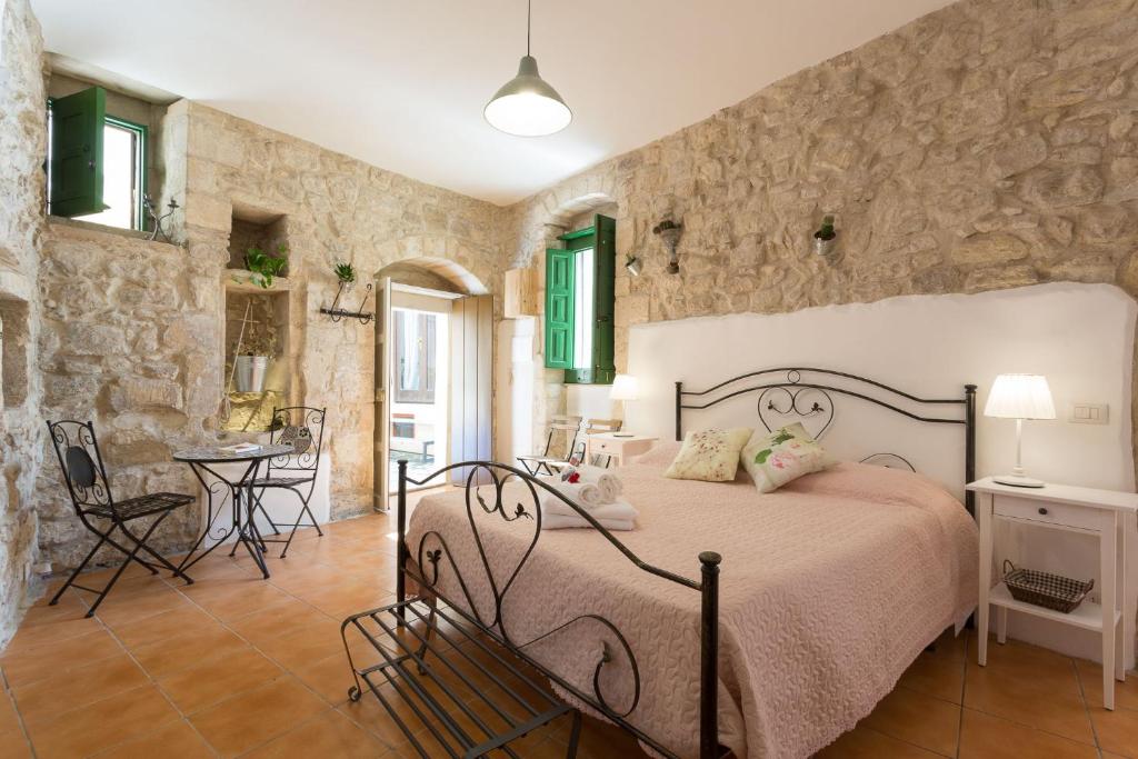1 dormitorio con cama y pared de piedra en Pura Vida Iblea, en Ragusa