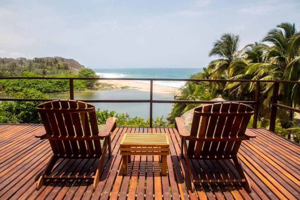 twee stoelen op een terras met uitzicht op het strand bij Senda Maloka Barlovento in Los Naranjos