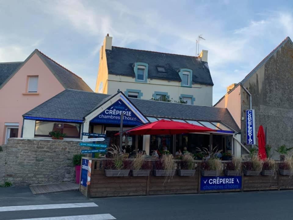 a building with a red umbrella in front of it at Le Trymen in Saint-Guénolé