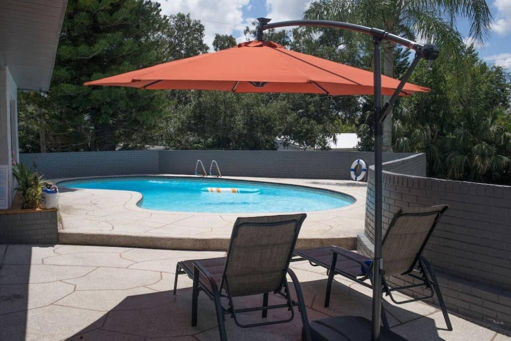 a patio with two chairs and an umbrella next to a pool at Sunset Oasis in Tampa