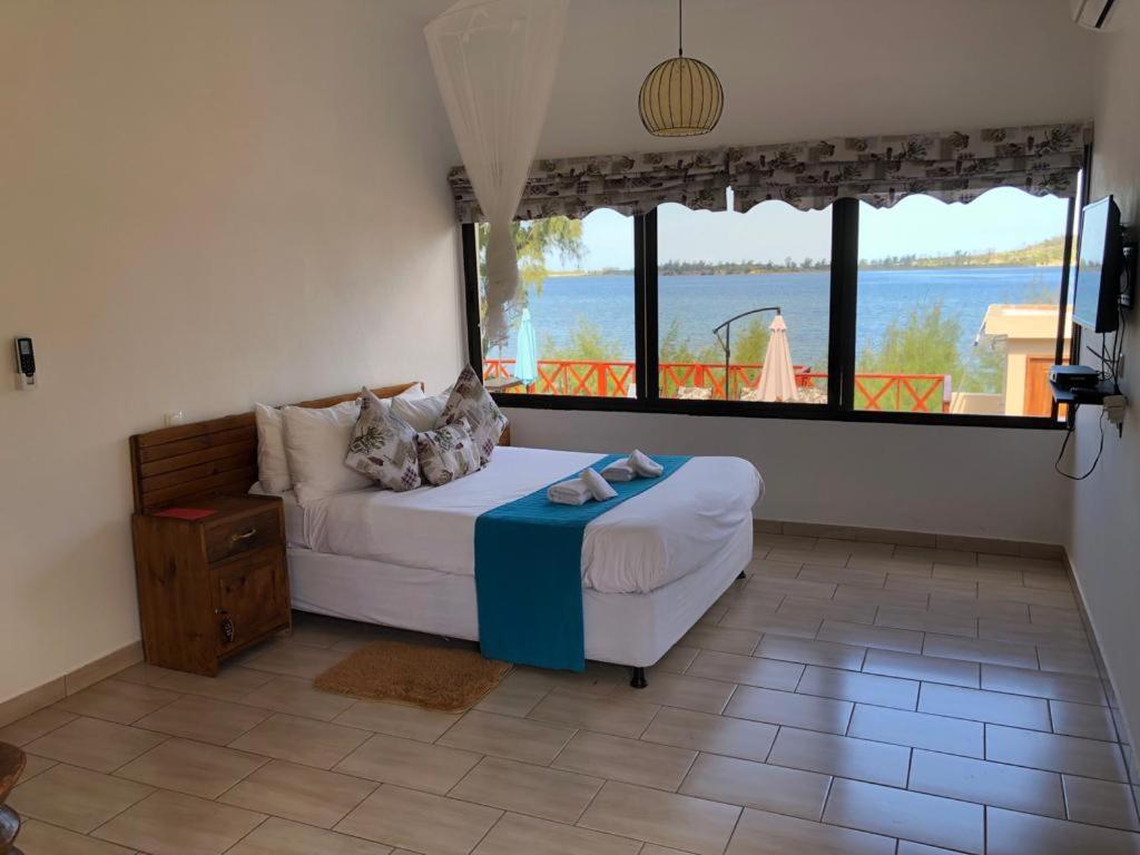 Dormitorio con cama y vistas al agua en Villa Espanhola Bilene, en Vila Praia Do Bilene