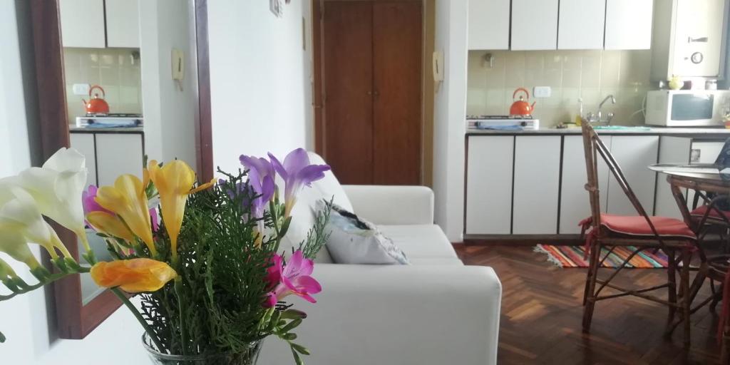 a living room with a white couch with flowers in a vase at Dpto El Cairo, tu lugar en Rosario in Rosario