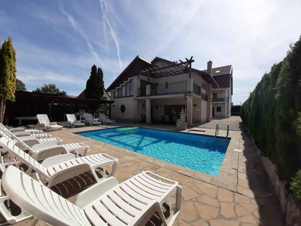a villa with a swimming pool and lounge chairs at Família Apartmanház in Keszthely