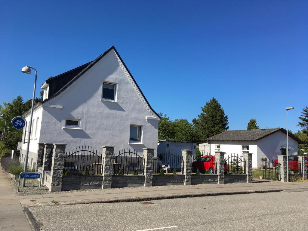 une maison blanche avec une clôture à côté d'une rue dans l'établissement Grenaa Bed and Breakfast, à Grenå