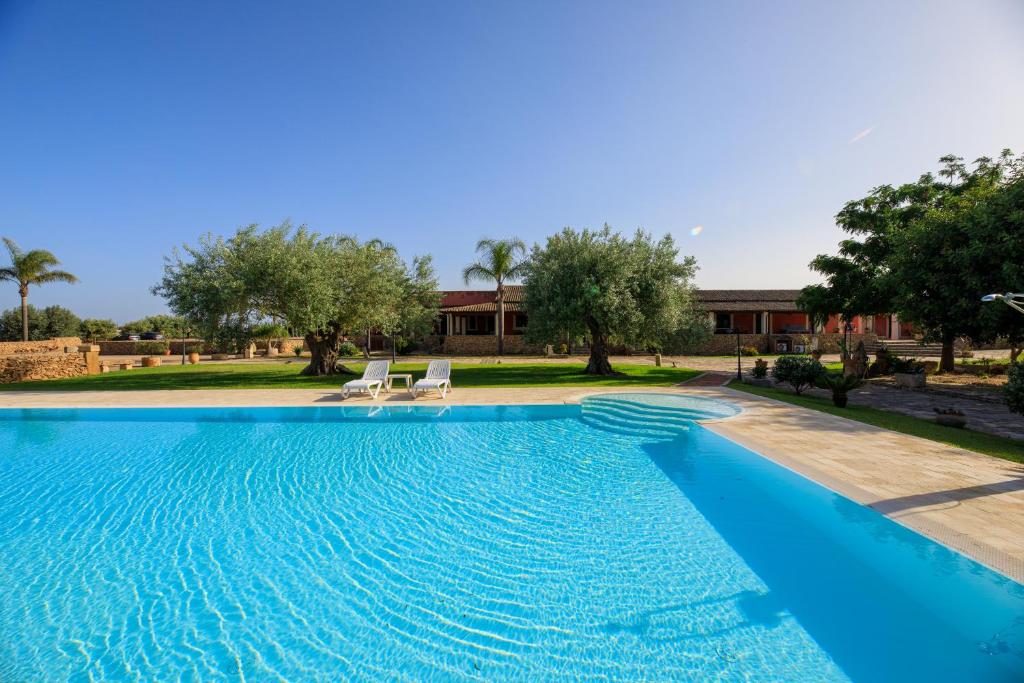 a swimming pool with two chairs and a house at Agriturismo Masseria Sant' Elia in Arenella