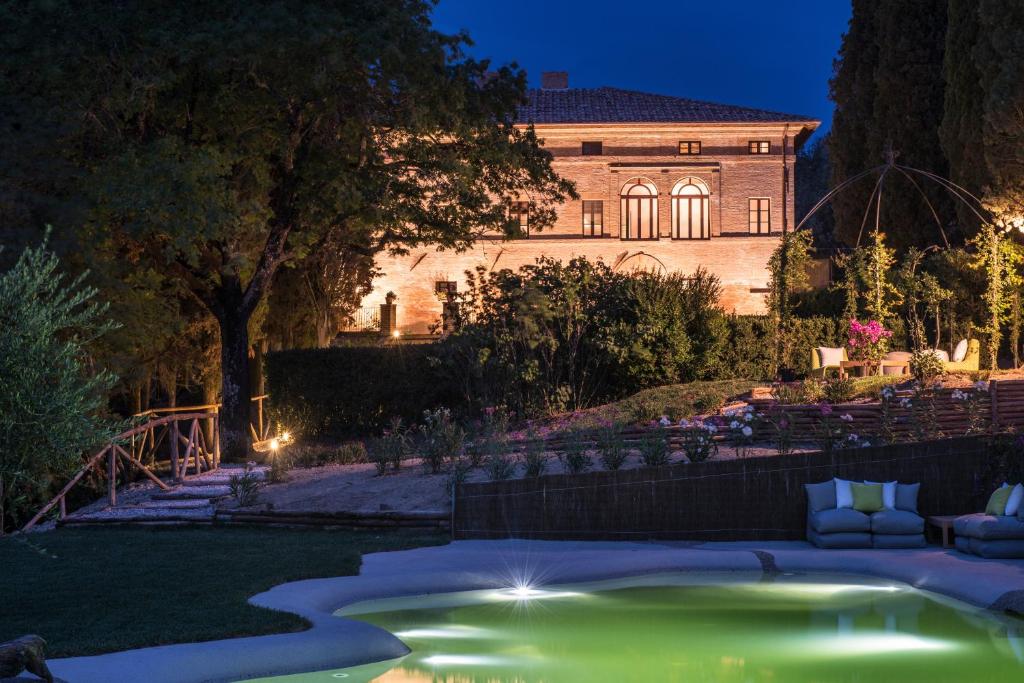 a garden with a pool in front of a building at Villa Armena Relais in Buonconvento