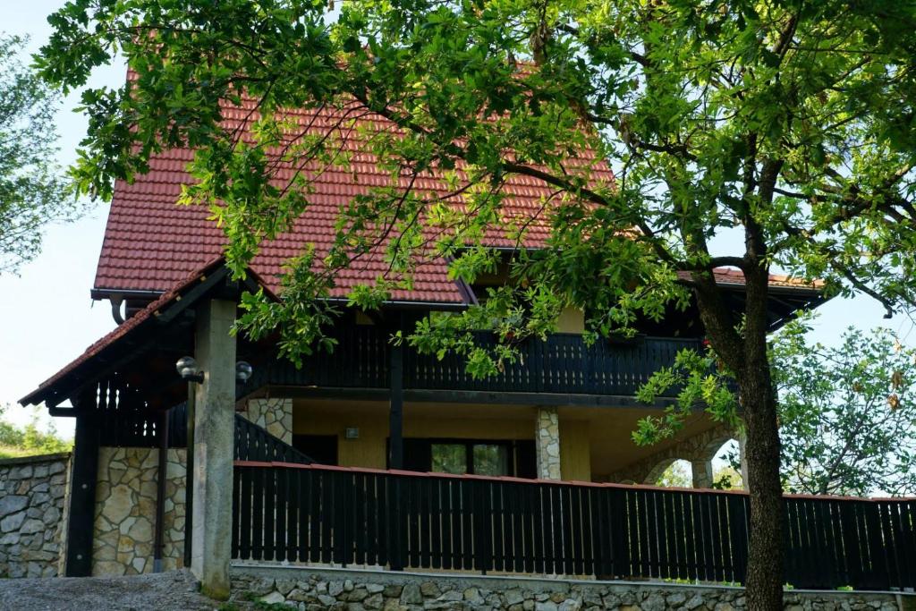 een huis met een rood dak en een boom bij kuća za odmor Krašić in Donje Prekrižje