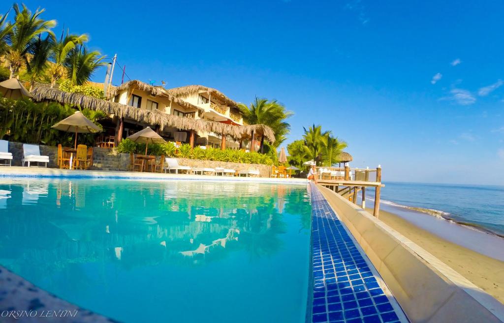 una piscina junto a una playa con un complejo en Hotel Grandmare & Bungalows, en Máncora