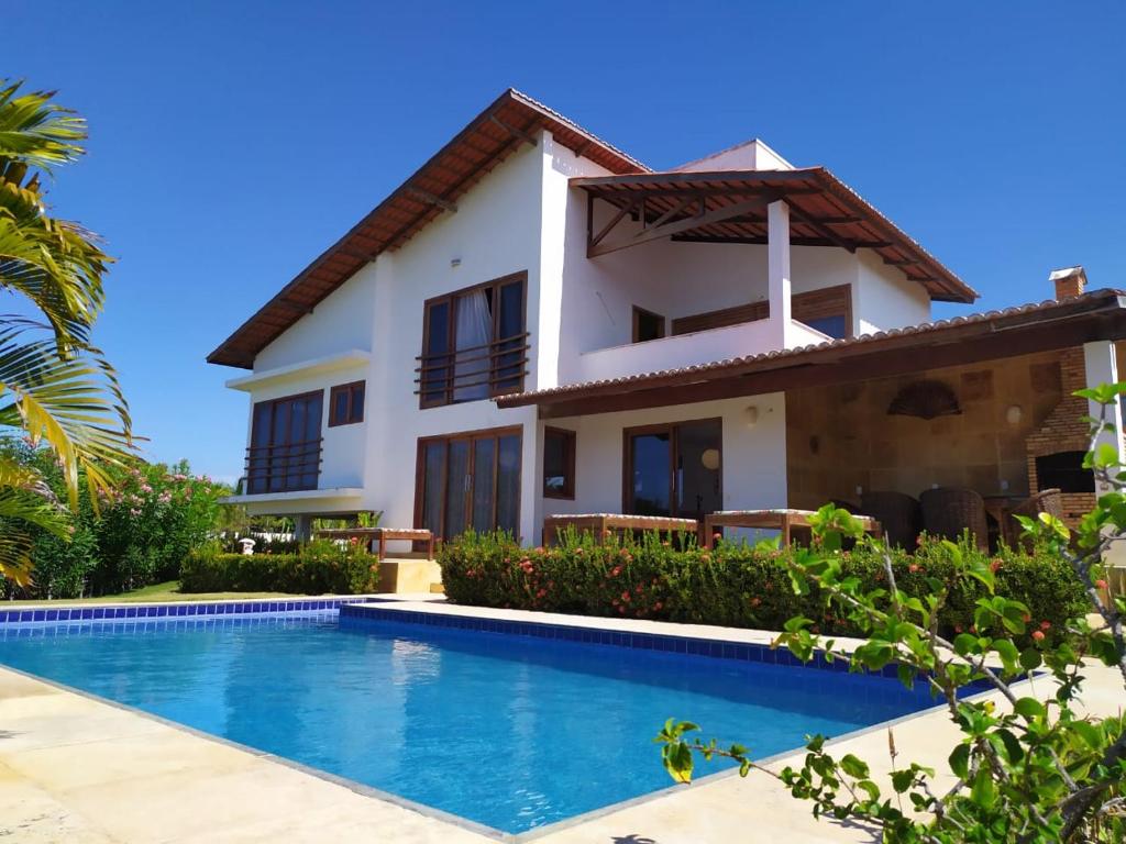 a villa with a swimming pool in front of a house at Refugios Parajuru - Casa Graf in Parajuru