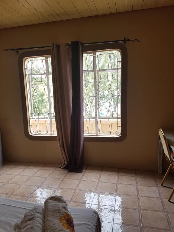 a room with two windows and a bed in it at one bedroom with attached bathroom in Rivière Noire