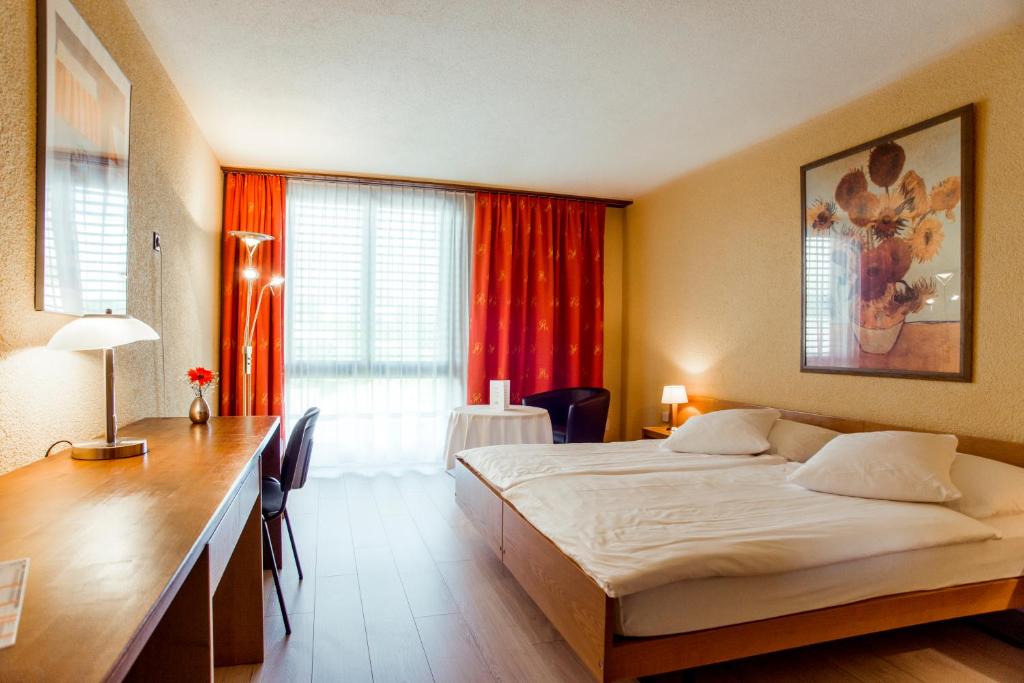 ドレモンにあるHôtel Le Nationalのベッドとデスクが備わるホテルルームです。
