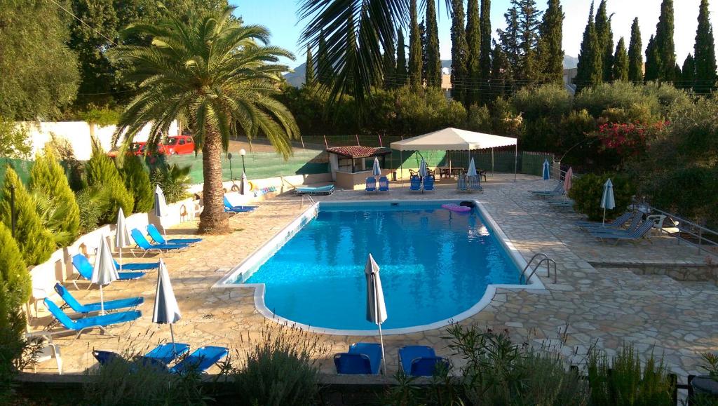 a swimming pool with blue chairs and umbrellas at Tina Hotel in Dassia