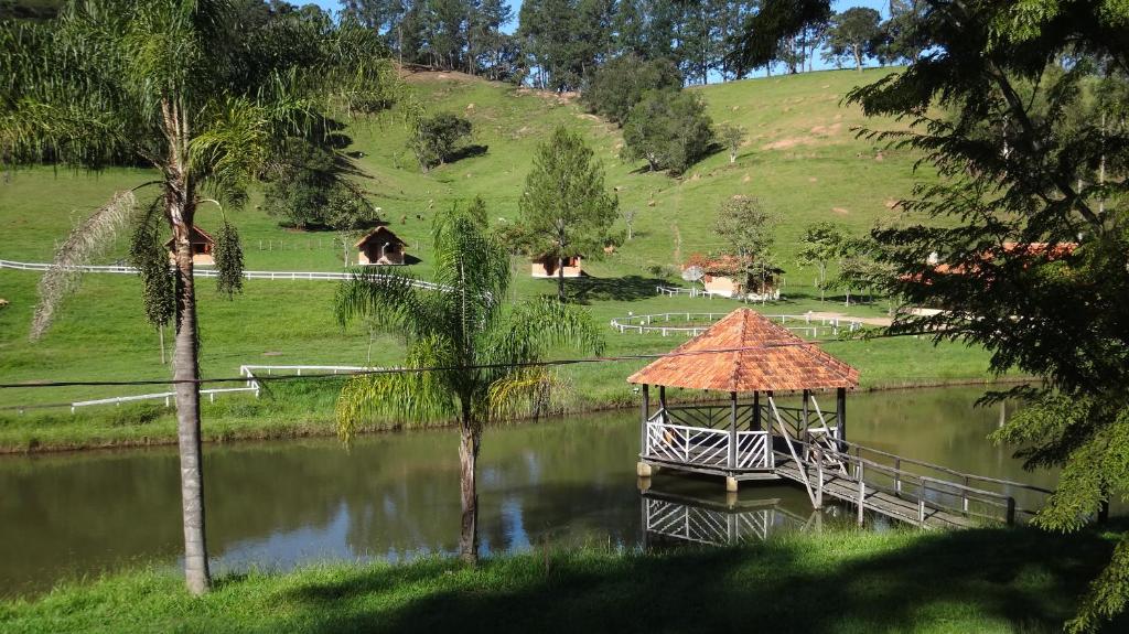 a boat in a lake with a bridge and trees at Pousada Colar de Ouro Chalés in Cunha