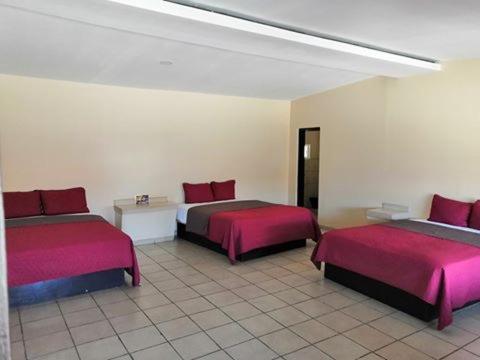 een kamer met twee bedden met roze lakens erop bij Motel Ranchito in Ensenada