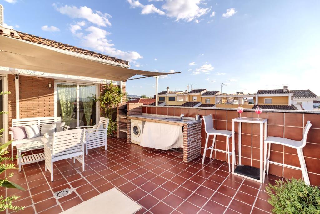 una casa con patio con sillas y bañera de hidromasaje. en Atico Escapada a Granada, en Granada