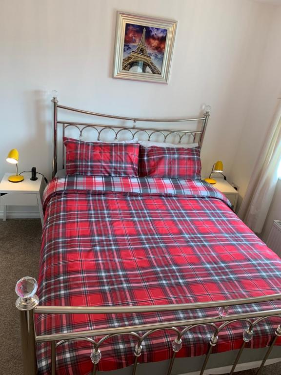 1 cama con edredón rojo a cuadros y 2 almohadas en Hollybrae house Sleeps up to 6, en Kirkcaldy
