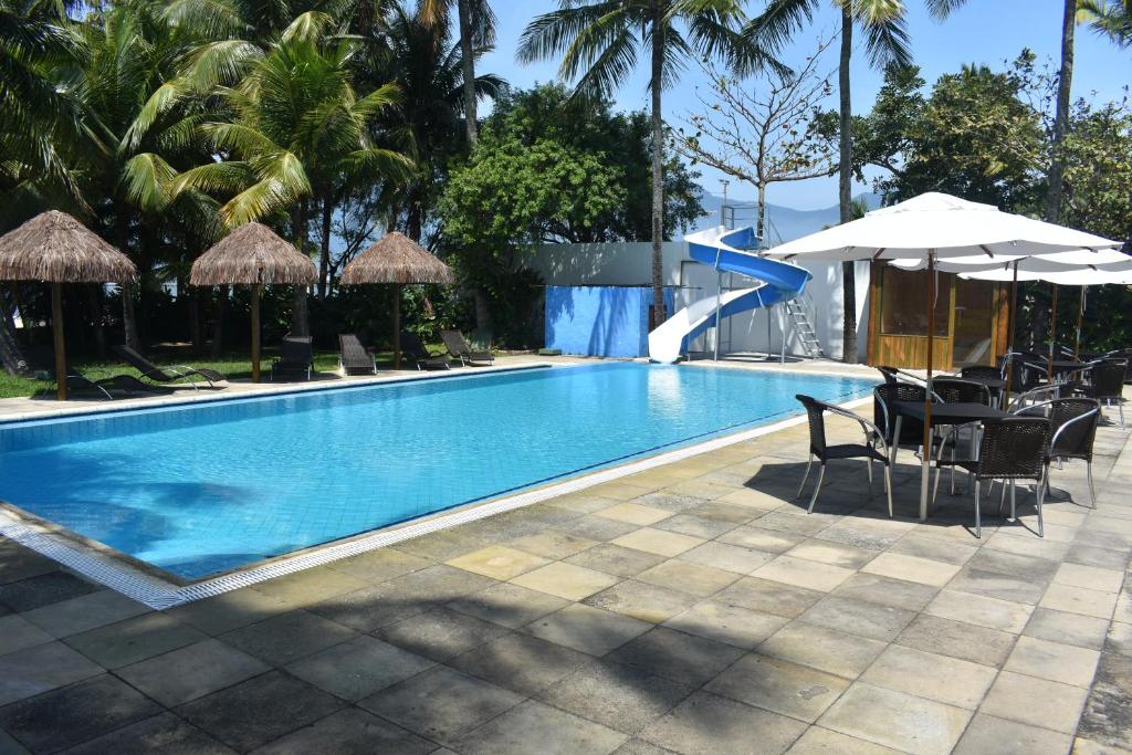 einen Pool mit Stühlen und Sonnenschirmen in einem Resort in der Unterkunft Porto Grande Hotel & Convention in São Sebastião