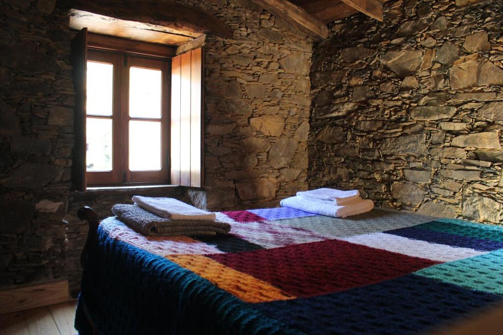 1 dormitorio con una manta colorida en la cama en Casa de Cima, en Lousã