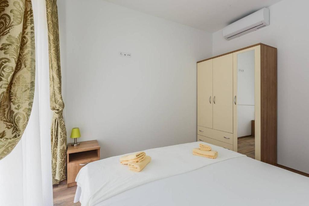 ein Schlafzimmer mit einem weißen Bett und einem Schrank in der Unterkunft Apartmani Nikola 3 in Trogir