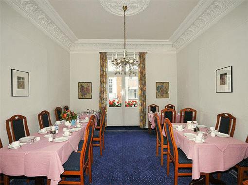 a dining room with pink tables and chairs and a chandelier at Hotel Bei der Esplanade in Hamburg