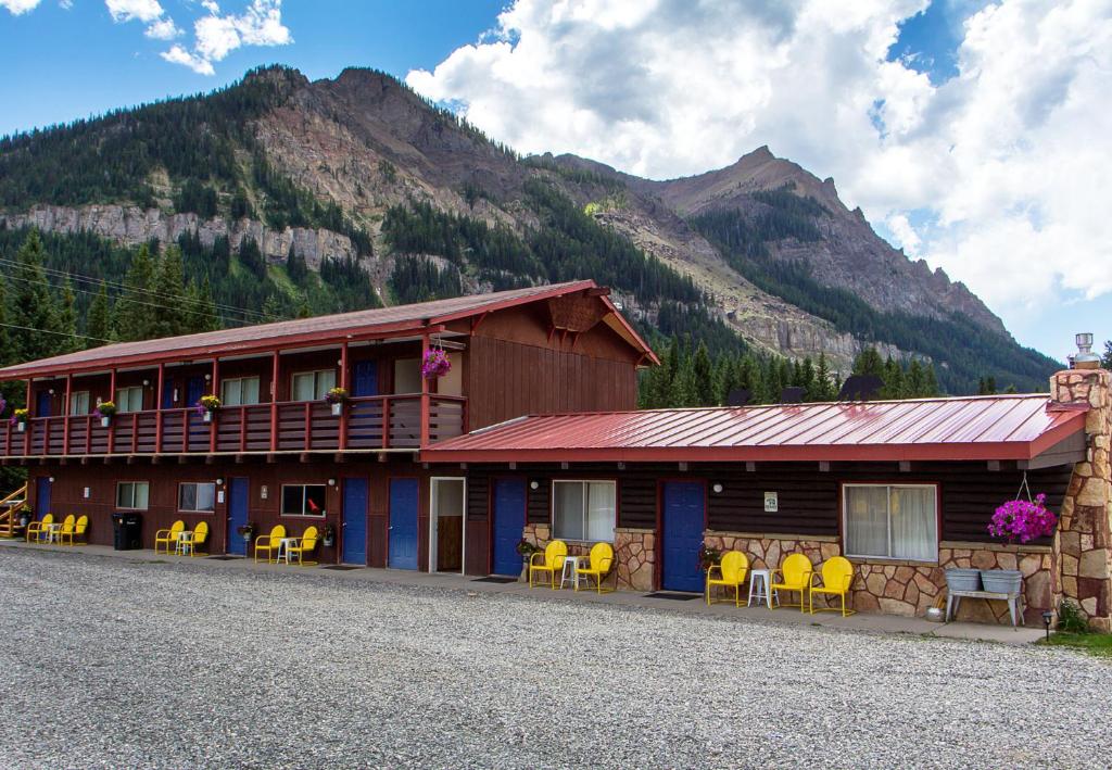 a building with yellow chairs in front of a mountain at High Country Motel and Cabins in Cooke City