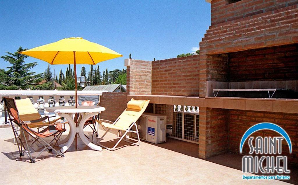 un patio con una mesa y una sombrilla amarilla en Saint Michel Departamentos para turismo en Alta Gracia
