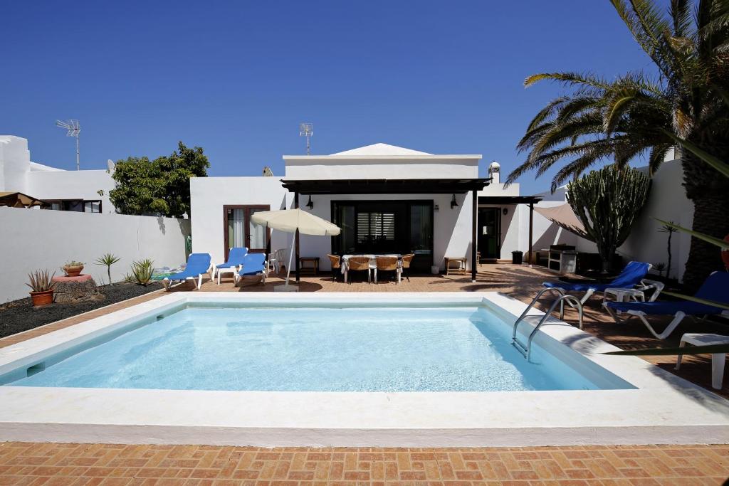 a swimming pool in front of a house at Villas Reina in Costa Teguise