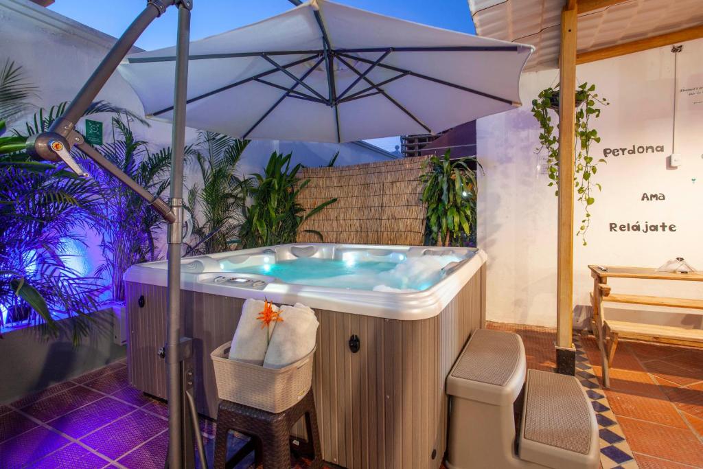 Mucura Hotel & Spa في كارتاهينا دي اندياس: حوض استحمام ساخن مع مظلة على الفناء